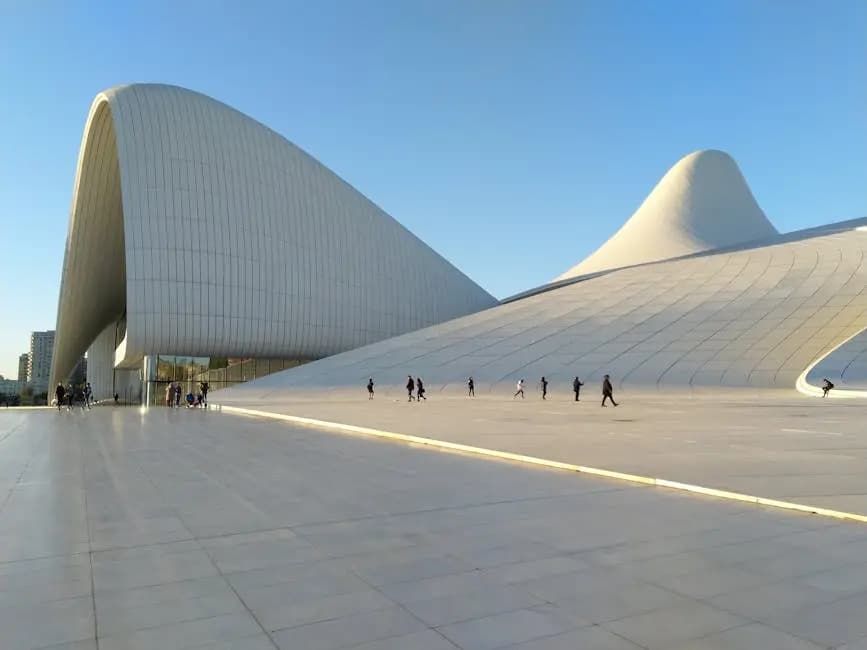 Striking modern architecture of the Heydar Aliyev Center in Baku with people walking under clear skies.